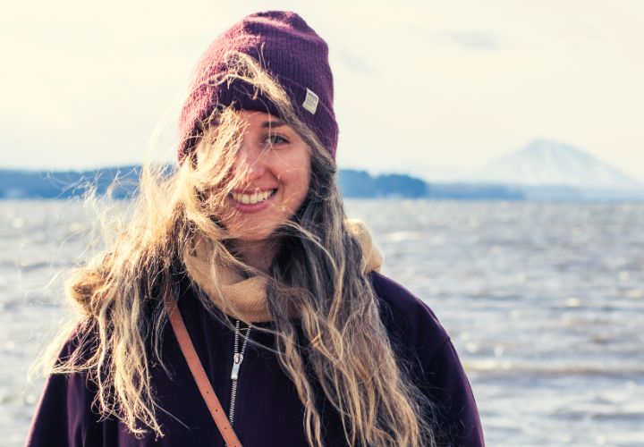 Une jeune femme dans un paysage montagneux. Ses cheveux enrobent son visage à cause du vent.